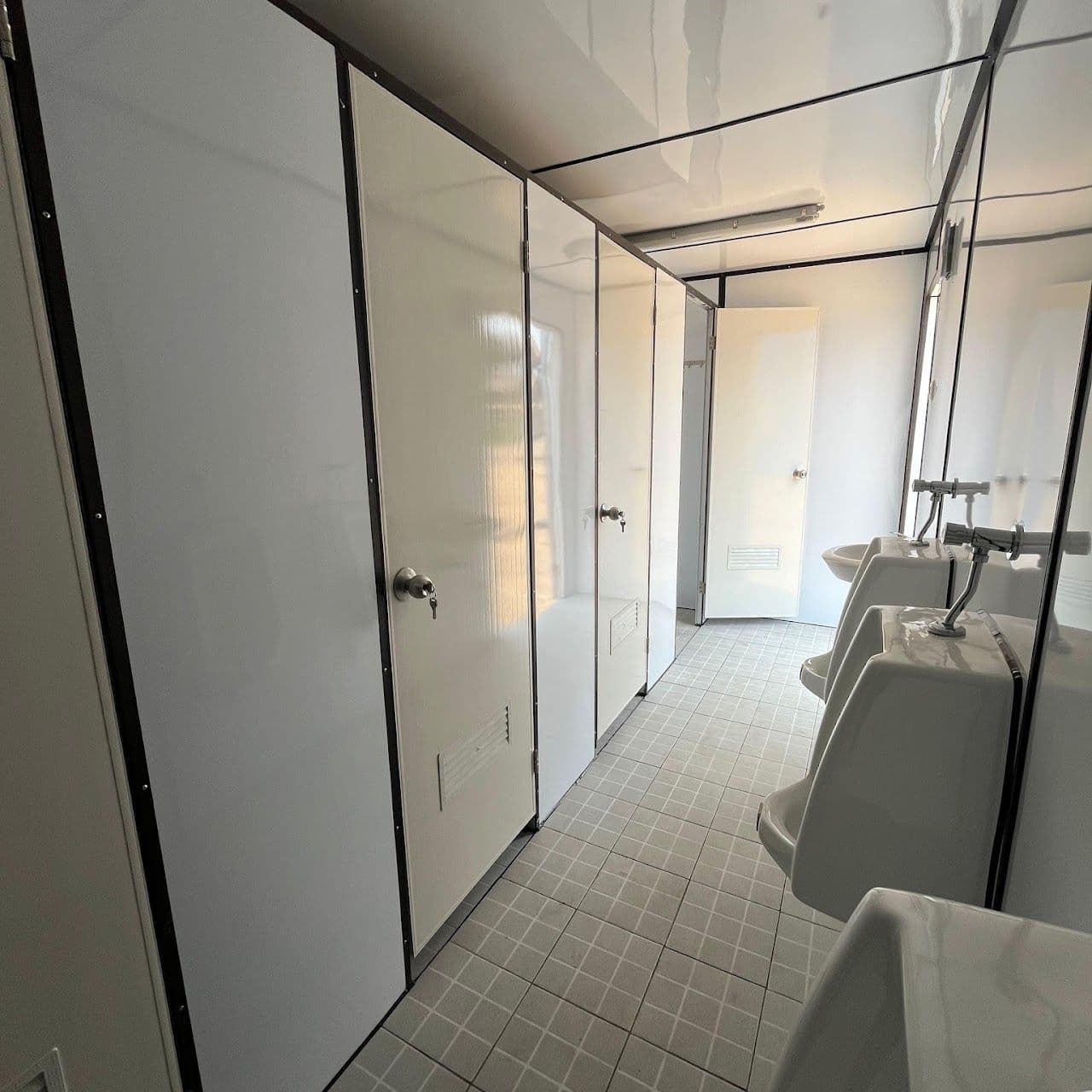 Deretan bilik toilet dan urinoir di dalam container